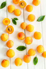 Apricots and leaves pattern on white wooden background top view