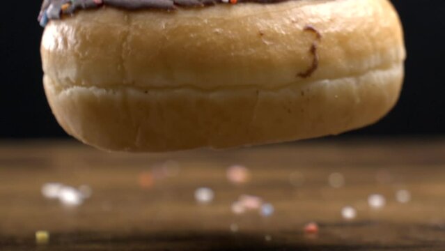 Large carb food snack falls into table surface in macro captured in slow-motion, Large chocolate donut