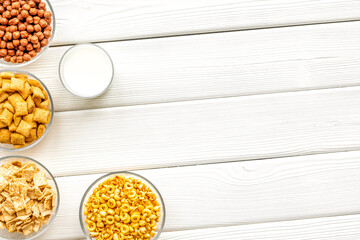 cereals, oatflakes and cornflakes with milk for healthy breakfast on white wooden background top view mock up