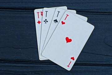 four white paper playing cards aces lie on a black wooden table