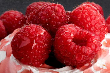 extreme macro closeup of red raspberries in a meringue shell with a black background