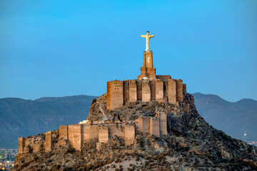 View of the medieval castle of Monteagudo with its Christ on top, Murcia, Spain, in early morning light