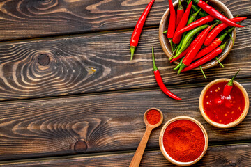 Fresh and powdered red and green chilli pepper pattern on wooden table background top view space...