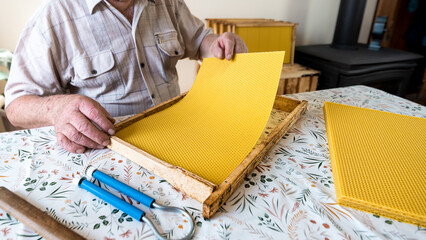 The beekeeper makes the beehive frames with wax foundation. Inserting the wax foundation on the...