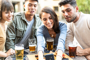 Shared joy over food and drinks. A diverse group of millennials engages happily with technology and each other, a true urban lifestyle snapshot.