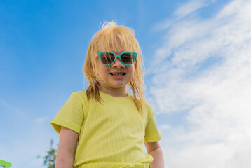 niña albina mirando al frente y usando lentes en un fondo del cielo azul  - obrazy, fototapety, plakaty