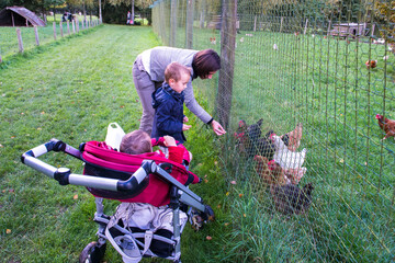 en famille à la ferme, enfants et leur mère nourrissant des poules à la campagne