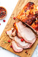 Baked festive pork sirloin with spices and cranberries for sauce, served and sliced on wooden cutting board, white table background, top view