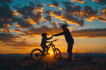 Fototapeta premium Silhouettes of two mountain bikers share a high five, celebrating a ride at sunset with the majestic backdrop of canyon silhouettes.