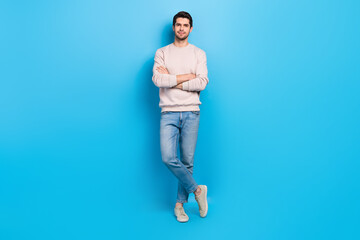 Full length photo of good mood pretty guy dressed beige sweatshirt arms crossed isolated blue color...