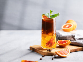 Coffee with orange juice (bumble) in a tall glass with ice and mint on a wooden board on a light background - obrazy, fototapety, plakaty