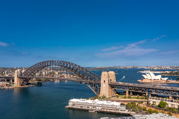 Panoramic view of Sydney Arch Bridge across the Tasman Sea behind the modern buildings of the city.