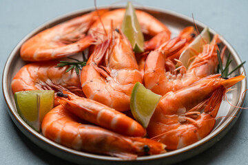 Fresh shrimps with ice, lime and rosemary on grey background, top view