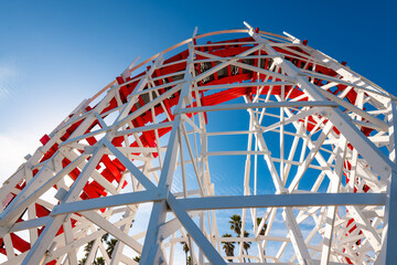 Wooden roller coaster at a funfair. Colorful red and white painted historic wooden structure of a...