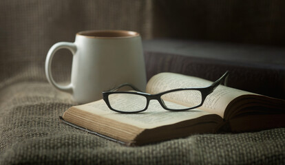 The glasses are on an old book. There is a mug and a burlap bag next to it