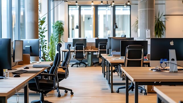 A bright modern office space with computers and comfortable chairs along large communal desks