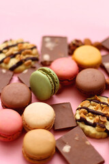 Pastel macarons, almond chocolate, peanut butter cookies and various nuts on bright pink background. Selective focus.
