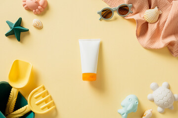 Baby sunscreen cream tube mockup with sunglasses, sand molds, seashells on beige background.