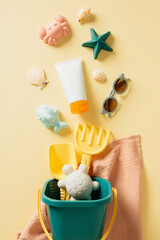 Flat lay composition with sunscreen cream, bucket with sand molds, seashells on beige background.