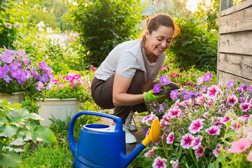 Gardening and agriculture concept. Young woman farm worker gardening flowers in garden. Gardener...