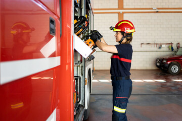A woman in her 40s and 50s works as a firefighter in uniform.The adult girl is pulling tools from...