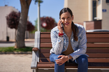 Beautiful woman talking on the phone while seated on a bench