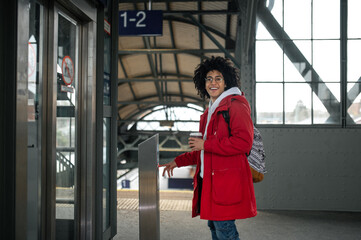Curly-haired young guy in red jacket at the railway station