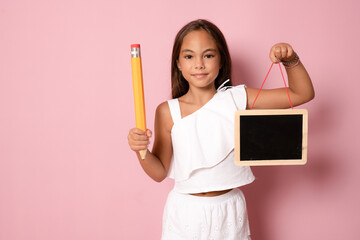 schoolgirl holding a tablet in her hands on a pink background. happy schoolgirl