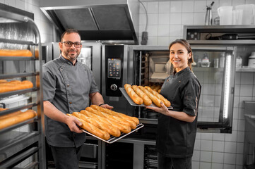 Man and woman working in a bakery and looking contented