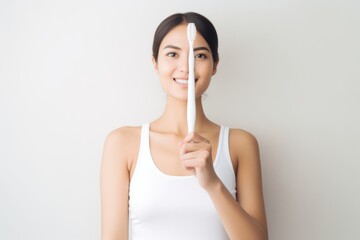 A cheerful woman holding a toothbrush to her eye, representing oral hygiene and dental care.