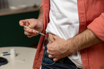 Sick man making medical diabetes insulin syringe injection into abdomen