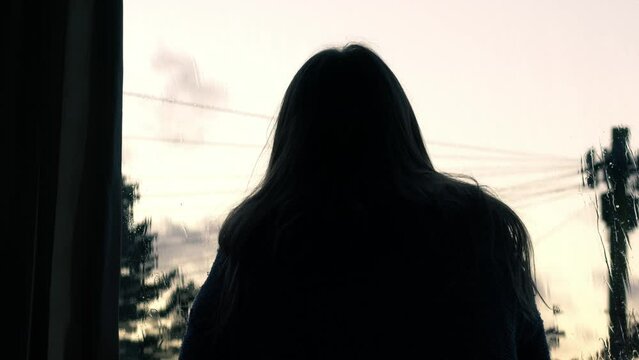 Woman looking out of window on rainy day 