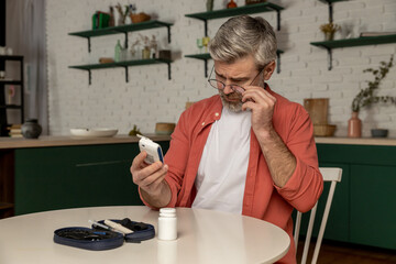 Middle aged man with glucometer checking blood sugar level at home