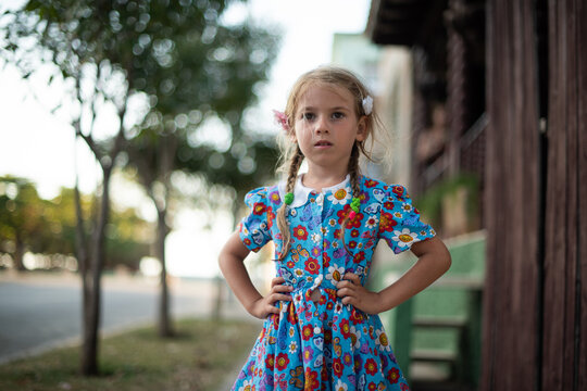 blonde girl in a flowered dress stands on the street of Cuba, child on Cuba, Cuban child, baby posing