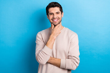 Photo of pleasant handsome man with stylish haircut dressed beige sweatshirt arm touch chin smiling...
