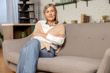 Blonde mid aged woman sitting on the sofa at home