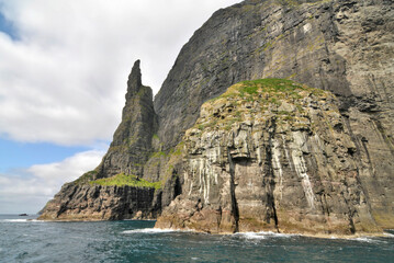 Fototapeta na wymiar Trøllkonufingur - imposing rock pillar rising from the sea at the coast of Vágar on the outskirts of Sandavágur.