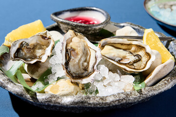 Closeup horizontal view of fresh oysters with lemon on ice, an upscale restaurant dish presentation