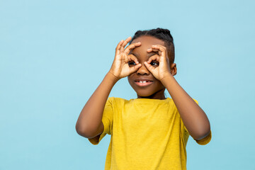 Funny dark- skinned little boy looking with hands binoculars