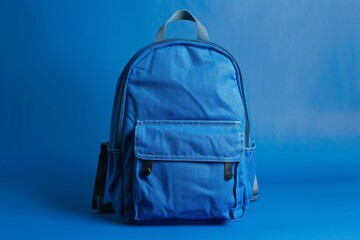 A neatly presented blue backpack isolated against a vibrant blue background in a studio setting