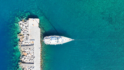 Aerial drone top view photo of beautiful sail boat anchored in Mediterranean destination port with crystal clear emerald sea