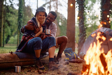 Naklejka na ściany i meble Young happy couple enjoying by campfire in woods.