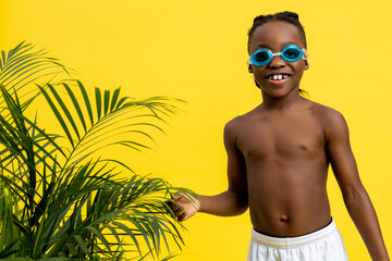 Dark-skinned boy on yellow background looking excited and contented