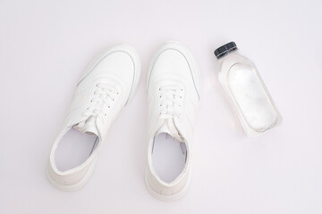  Sports shoes with bottle of water on white background: white sneakers for men and women.