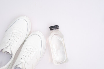  Sports shoes with bottle of water on white background: white sneakers for men and women.
