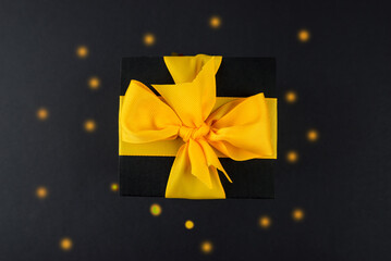 Top view photo of a black gift box with a yellow bow