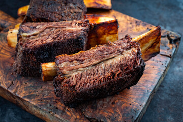 Traditional barbecue burnt chuck beef ribs marinated with spicy rub and served as close-up on an old rustic wooden board