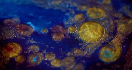 Shiny paint. Sparkling oil drops. Ink fluid. Defocused blue purple golden color metallic dust...
