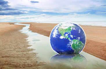 Hope to save the Earth concept, Globe earth on sand by the sea on a bright day, Elements of this image furnished by NASA