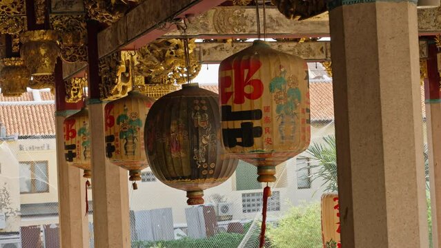 Row of four Chinese Lanterns swaying back and forth in the wind in front of the Leong San Tong Khoo Kongsi temple and clanhouse in George Town, Penang, Malaysia